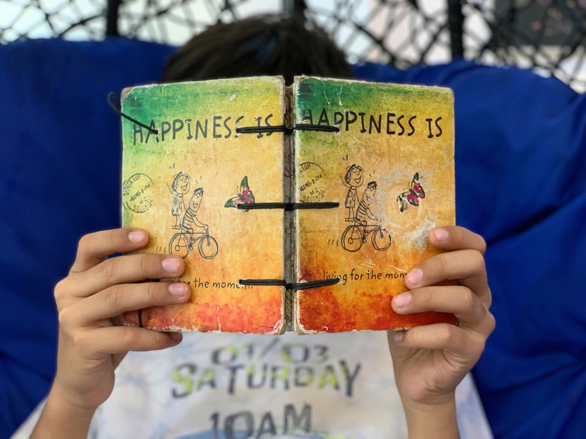 A child holding up a handmade illustrated memory journal